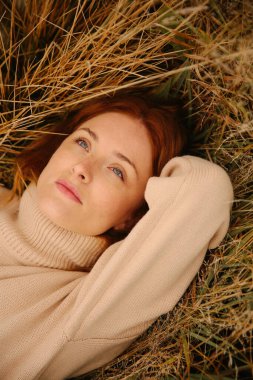 Genç kızıl saçlı bir kızın sonbahar portresi, sonbahar tarlasında bir yürüyüş.