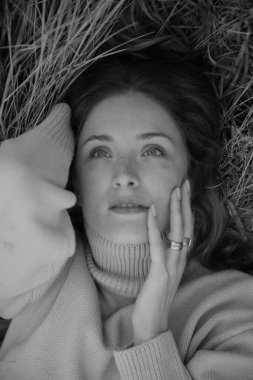 Rus tarlasında bir kız çimenlerde uzanıyor, siyah beyaz sonbahar fotoğraf çekimi.