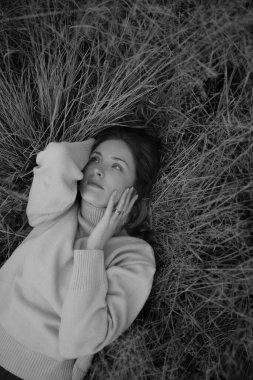 Rus tarlasında bir kız çimenlerde uzanıyor, siyah beyaz sonbahar fotoğraf çekimi.