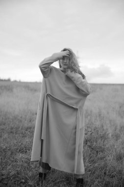 Doğada paltolu bir kadının melankolik siyah beyaz portresi. Bulanık fotoğraf, bulanık.