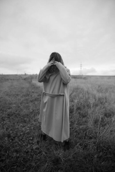 Melancholic black and white portrait of a woman in nature in a coat. Blurry photo, blurring