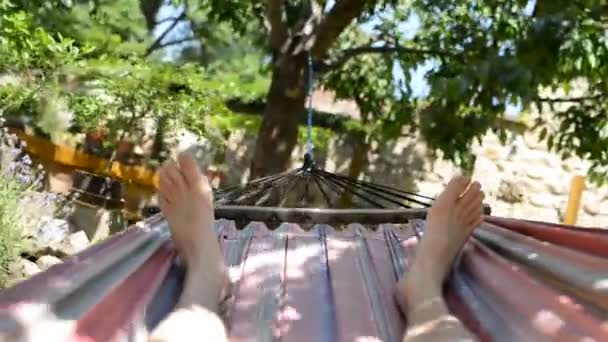 Человек лежит в гамаке в саду — стоковое видео