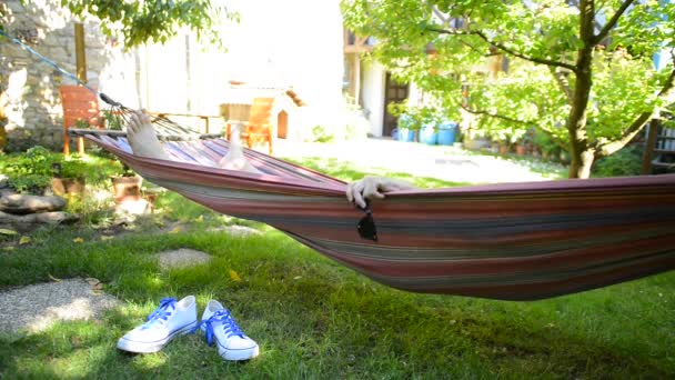 Mann liegt in einer Hängematte im Garten — Stockvideo