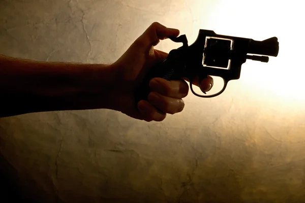 Silhueta de uma mão de homem com uma arma — Fotografia de Stock