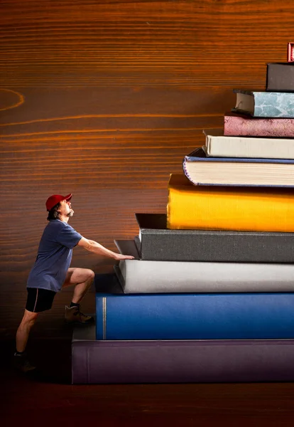 Bergsteiger klettert auf Bücherhaufen — Stockfoto