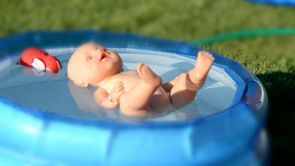 Eine Puppe, die im kleinen Kinderbecken schwimmt — Stockvideo