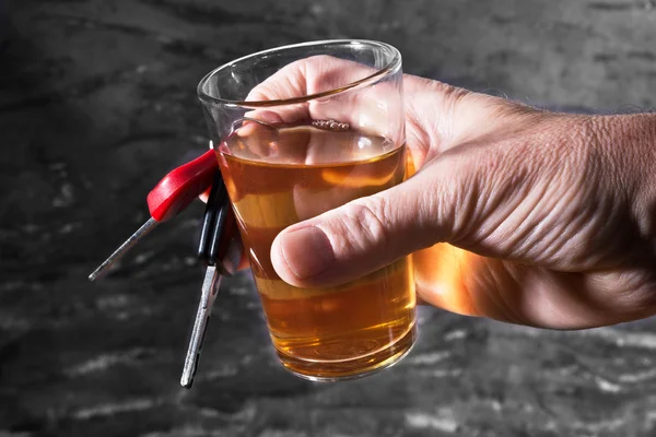 Man behind car key and glass of liqueur — Stock Photo, Image