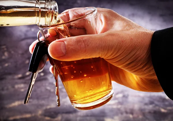 Man met auto sleutel en glas met alcohol — Stockfoto