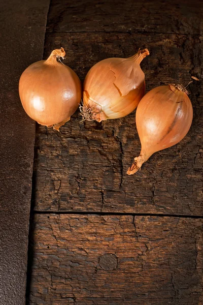 Três oninons na mesa de madeira — Fotografia de Stock