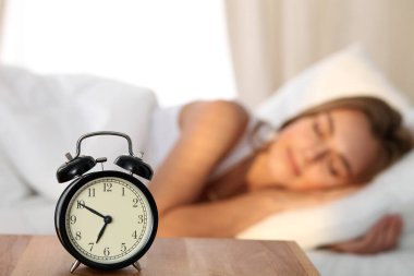 Yatakta rahat ve mutlu bir şekilde yatarken uyuyan ve gülümseyen güzel genç bir kadın çalar saatin arka planında çalacak. Gün ışığı yüzünü aydınlatıyor..