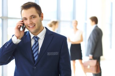 Ofiste gülümseyen işadamı ve arka planda iş arkadaşları