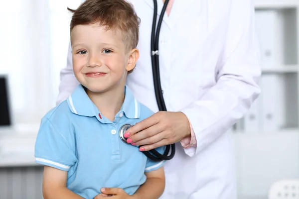 Dottore e paziente in ospedale. Buon bambino che si diverte mentre viene esaminato con lo stetoscopio. Concetto sanitario e assicurativo — Foto Stock