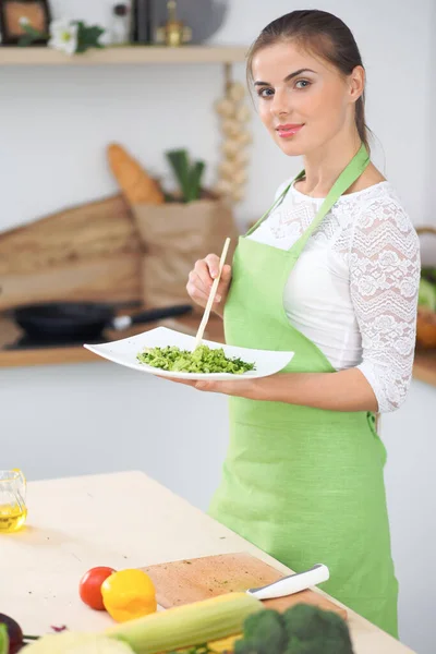 年轻的家庭主妇在厨房做饭。在家享用新鲜健康食物的概念 — 图库照片