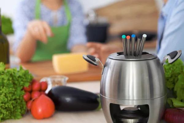 Fondue i en kruka i bakgrunden av vänner matlagning tillsammans, närbild. Köksinredningar och köksredskap — Stockfoto