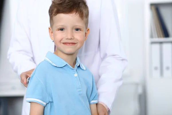Médico y paciente en el hospital. Feliz niño divirtiéndose mientras es examinado con estetoscopio. Concepto de asistencia sanitaria y seguros — Foto de Stock