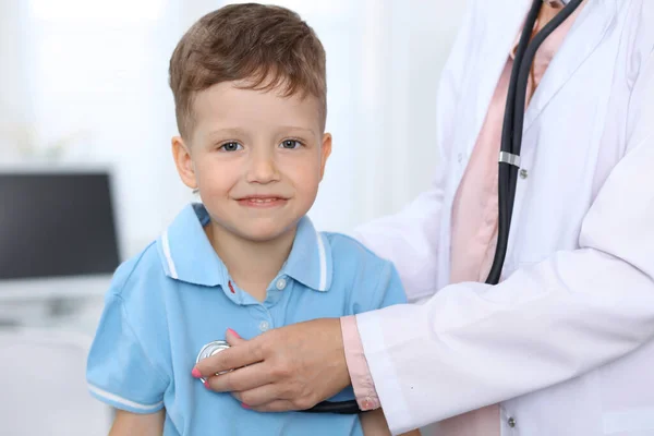 Dokter en patiënt in het ziekenhuis. Gelukkige kleine jongen die plezier heeft terwijl hij wordt onderzocht met stethoscoop. Gezondheids- en verzekeringsconcept — Stockfoto