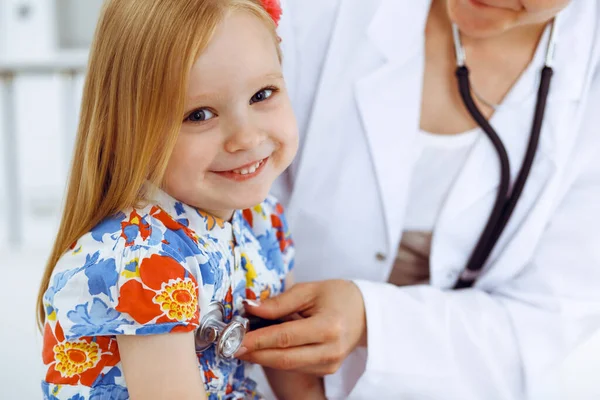 Feliz sorriso feminino criança-paciente na inspeção médica habitual. Médico e jovem na clínica. Medicina, conceitos de saúde — Fotografia de Stock