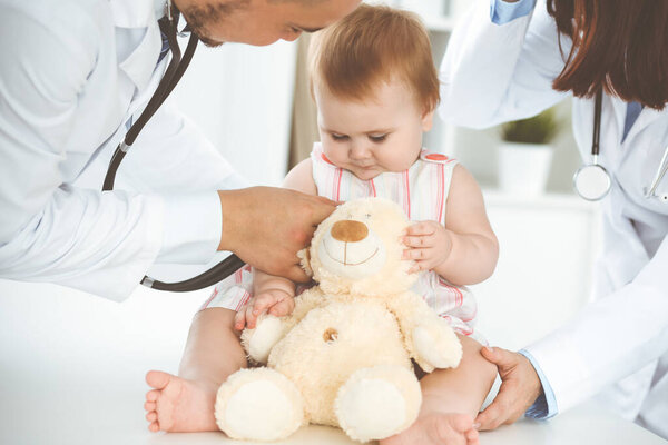 Happy girl-child at usual medical inspection. Doctor and female toddler patient in the clinic. Healthcare concept.