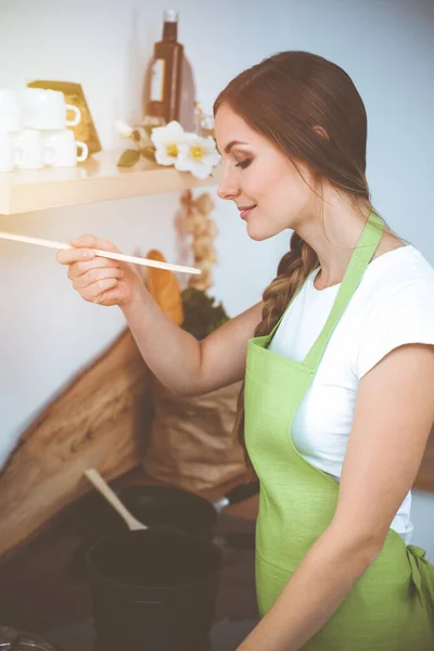 一位年轻貌美的女士站在阳光灿烂的厨房里用新的龙头香配汤 烹饪和持家概念 — 图库照片