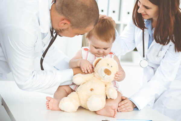 Happy girl-child at usual medical inspection. Doctor and female toddler patient in the clinic. Healthcare concept.