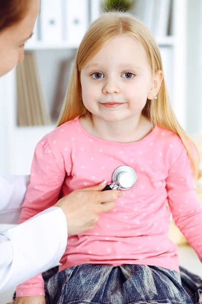 Gelukkige glimlachende vrouwelijke kind-patiënt bij de gebruikelijke medische inspectie. Dokter en jong meisje in de kliniek. Geneeskunde, gezondheidsconcepten — Stockfoto