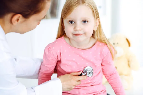 Gelukkige glimlachende vrouwelijke kind-patiënt bij de gebruikelijke medische inspectie. Dokter en jong meisje in de kliniek. Geneeskunde, gezondheidsconcepten — Stockfoto