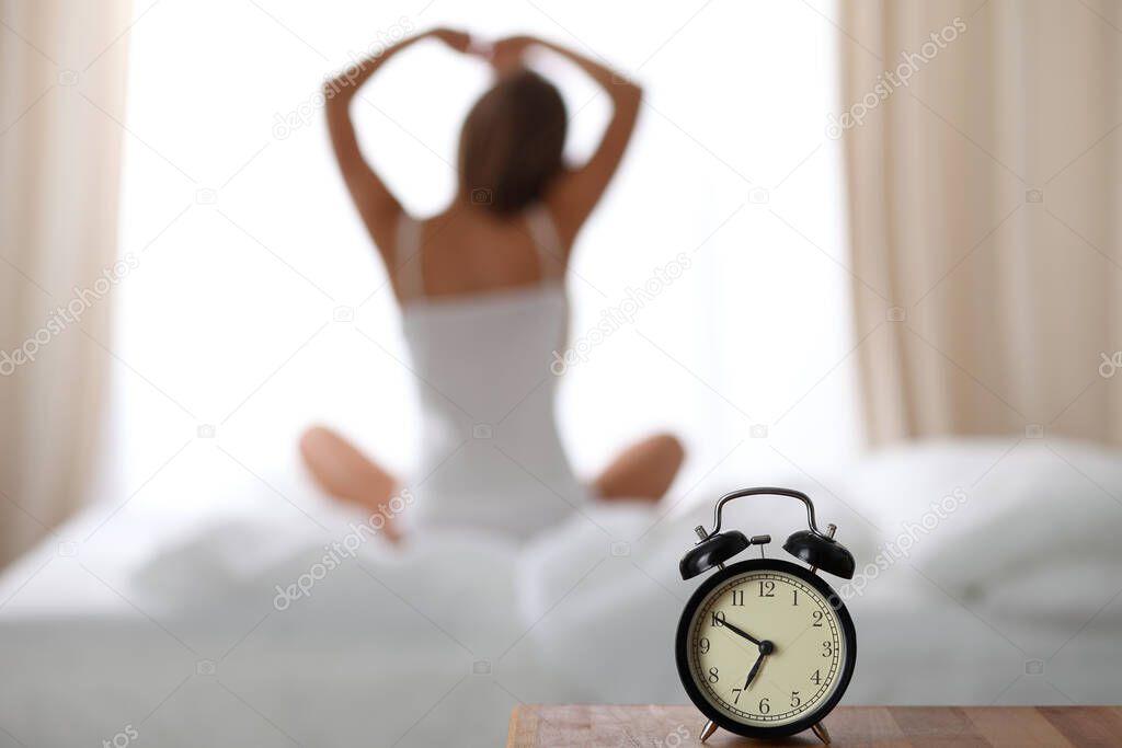 Woman stretching in bed after wake up, back view, entering a day happy and relaxed after good night sleep. Sweet dreams, good morning, new day, weekend, holidays concept.