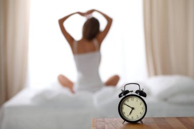 Kadın uyandıktan sonra yatakta geriniyor, geriye bakıyor, iyi bir uykudan sonra bir güne mutlu ve rahat giriyor. Tatlı rüyalar, günaydın, yeni gün, hafta sonu, tatil konsepti.