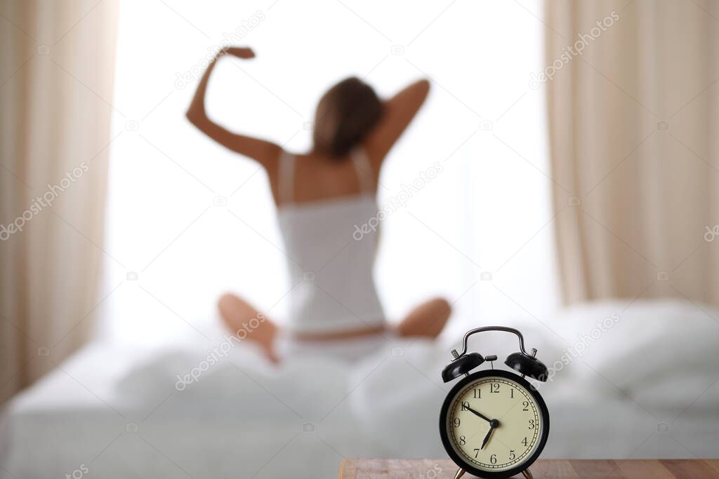 Woman stretching in bed after wake up, back view, entering a day happy and relaxed after good night sleep. Sweet dreams, good morning, new day, weekend, holidays concept.