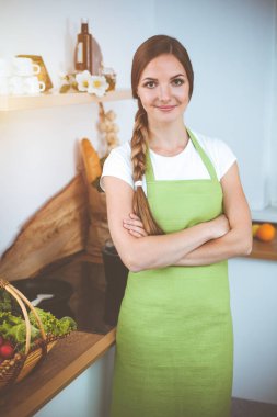 Çekici genç bir kadın, güneşli mutfakta dururken lezzetli bir salata karışımı için yeni bir tarif hazırlamaya hazır..