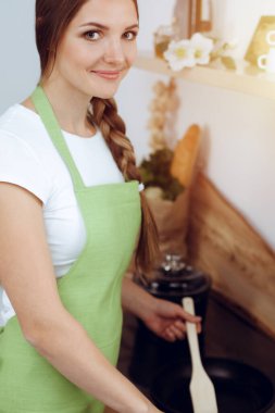 Çekici genç bir kadın, güneşli mutfakta dururken lezzetli bir salata karışımı için yeni bir tarif hazırlamaya hazır..
