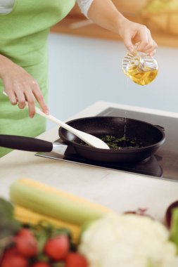 Çekici, genç, koyu renk saçlı bir kadın. Güneşli mutfakta ayakta durup gülümserken yeni keto tarifi ile solucan tavasında yemek pişiriyor. Yemek pişirme ve ev idaresi kavramları.