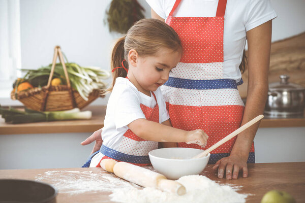 Счастливая женщина и ее дочь смешивают тесто и пекут печенье для вкусного семейного пира. Рождество, Новый год, День Благодарения, Юбилей, День Матери. Концепция здорового питания.