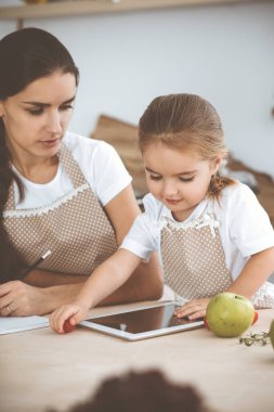 Mutlu kadın ve kızı lezzetli bir aile ziyafeti için yeni tarifler arıyorlar. Noel, yeni yıl, Şükran Günü, yıldönümü, anneler günü. Sağlıklı yemek pişirme kavramı.