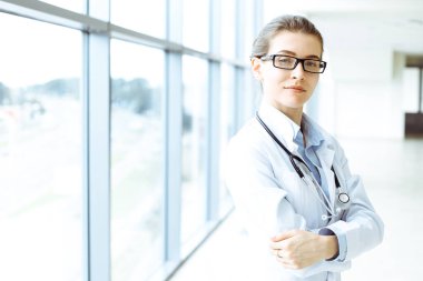 Steteskopla gülümseyen güzel kadın doktor modern hastanedeki hastalara yardım etmeye hazır. Tıp konsepti.