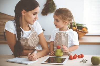 Mutlu kadın ve kızı lezzetli bir aile ziyafeti için yeni tarifler arıyorlar. Noel, yeni yıl, Şükran Günü, yıldönümü, anneler günü. Sağlıklı yemek pişirme kavramı.