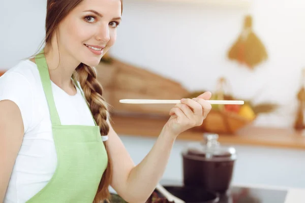 一位年轻貌美的女士站在阳光灿烂的厨房里用新的龙头香配汤 烹饪和持家概念 — 图库照片