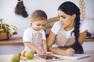 Mutlu kadın ve kızı lezzetli bir aile ziyafeti için yeni tarifler arıyorlar. Noel, yeni yıl, Şükran Günü, yıldönümü, anneler günü. Sağlıklı yemek pişirme kavramı.
