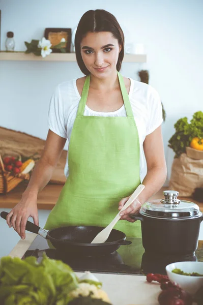 一位年轻迷人的黑头发女子一边站在厨房里 一边笑着 一边用新的酮菜谱在蠕虫盘中煎着饭 烹饪和持家概念 — 图库照片