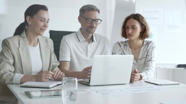Business team collaborating on a project, analyzing data on a laptop during a productive office meeting, demonstrating teamwork and problem solving skills