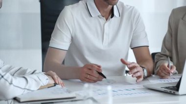 Business team collaborating in a modern office, analyzing financial data, discussing strategies, and reviewing charts and graphs during a productive meeting focused on growth and performance, close up