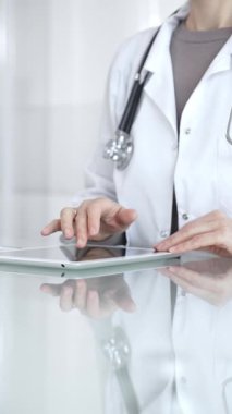 Steteskoplu beyaz önlüklü bir tıp uzmanı dijital sağlık hizmetleri, teletıp ve EMR veri incelemesi ve danışma için bir tablet kullanıyor. İlaç ve sağlık hizmetleri