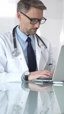 Beyaz önlük ve steteskop giyen doktor dizüstü bilgisayarda çalışıyor, teletıp danışmanlığı yapıyor ya da tıbbi rapor yazıyor. İlaç ve sağlık hizmetleri