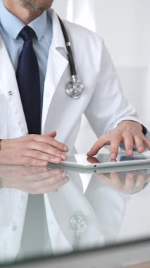 Doktor, teletıp, hasta verilerini ve sağlık teknolojisini temsil eden yansıtıcı bir masada dijital tablet tutuyor ve onunla etkileşime geçiyor. İlaç ve sağlık hizmetleri