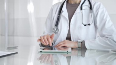 Doktor dijital tablete dokunuyor klinikteki tıbbi kayıtları inceliyor, sağlık uzmanı hastanedeki modern teknolojiyi kullanıyor. İlaç ve sağlık hizmetleri