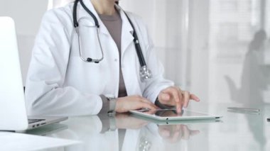 Doktor dijital tablete dokunuyor klinikteki tıbbi kayıtları inceliyor, sağlık uzmanı hastanedeki modern teknolojiyi kullanıyor. İlaç ve sağlık hizmetleri