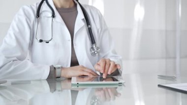 Doktor dijital tablete dokunuyor klinikteki tıbbi kayıtları inceliyor, sağlık uzmanı hastanedeki modern teknolojiyi kullanıyor. İlaç ve sağlık hizmetleri