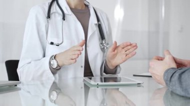 Doktor, klinik muayenesi, profesyonel bakım tartışması sırasında tıbbi verileri incelemek için tablet kullanan hastaya tedavi seçeneklerini açıklıyor. İlaç ve sağlık hizmetleri