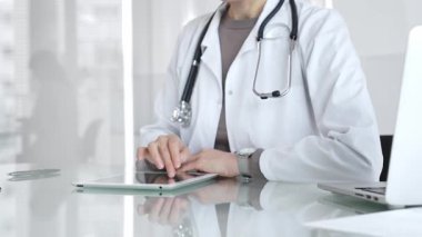 Doktor dijital tablete dokunuyor klinikteki tıbbi kayıtları inceliyor, sağlık uzmanı hastanedeki modern teknolojiyi kullanıyor. İlaç ve sağlık hizmetleri