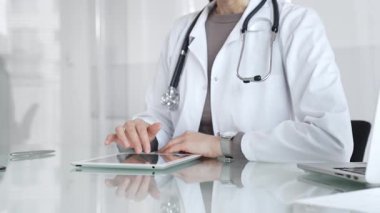 Doktor dijital tablete dokunuyor klinikteki tıbbi kayıtları inceliyor, sağlık uzmanı hastanedeki modern teknolojiyi kullanıyor. İlaç ve sağlık hizmetleri